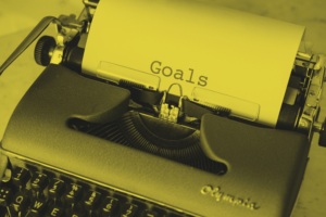 A vintage typewriter with a sheet of paper that has the word "Goals" typed in the center.